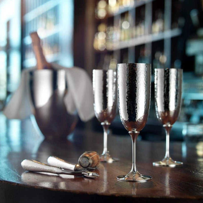 Set of silver wine glasses and Champagne tongs Martelé silver-plated by Robbe & Berking on a bar counter with blurred background