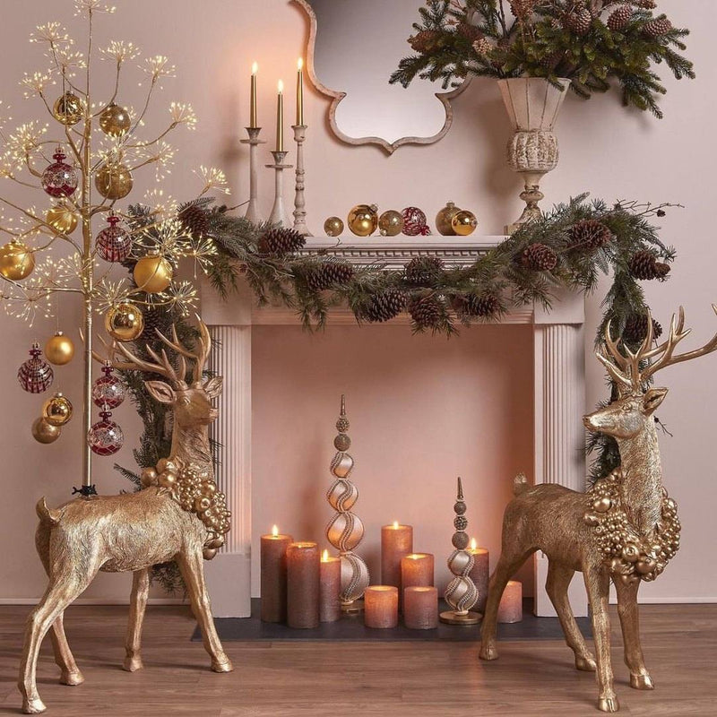 Decorative Christmas scene with gold deer, candles, and garlands in a room.