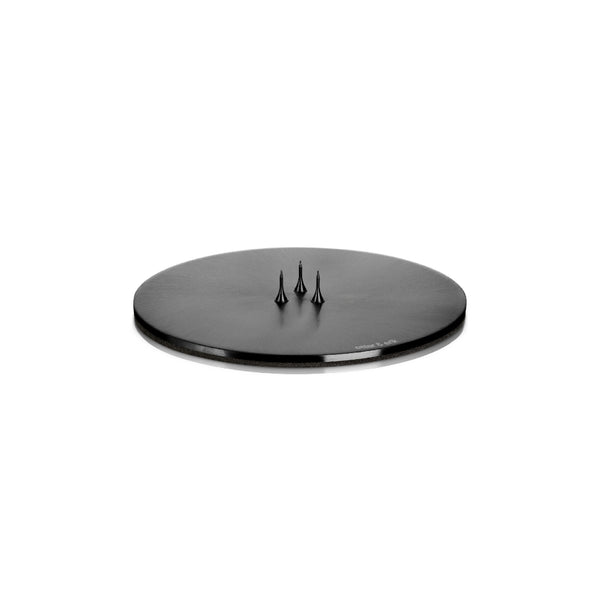 A round, matte black candle plate holder with three spikes on the top, designed to hold a candle securely.