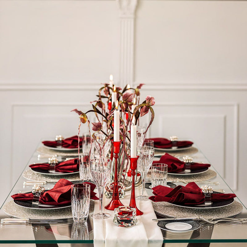 Elegant table setting with red napkins, candles, and floral arrangements in a formal dining room.