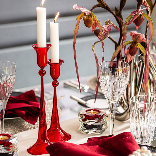 Decorative table setting with red candlesticks, crystal glasses, and floral arrangement.