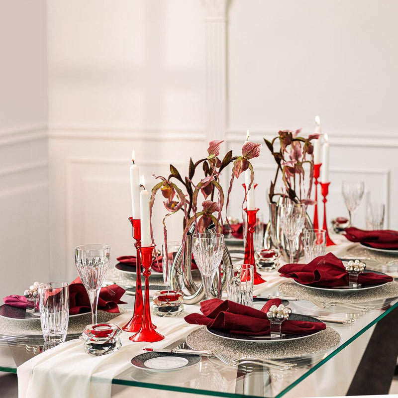 Elegant table setting with red napkins, candles, and floral arrangements in a formal dining room.