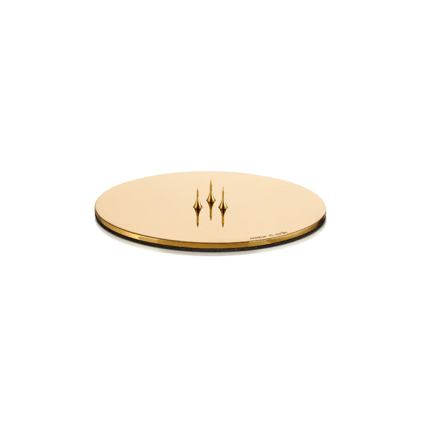 A round gold candle plate holder with a central spike for holding candles, featuring a foam backing.