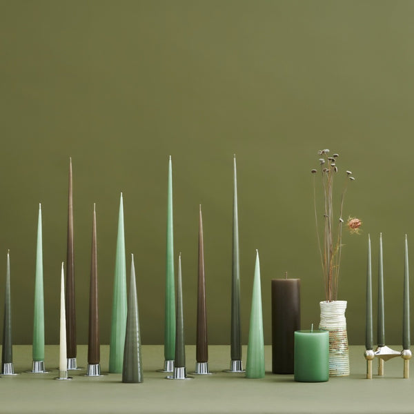 Set of tall, slender candles in various colors against a green background
