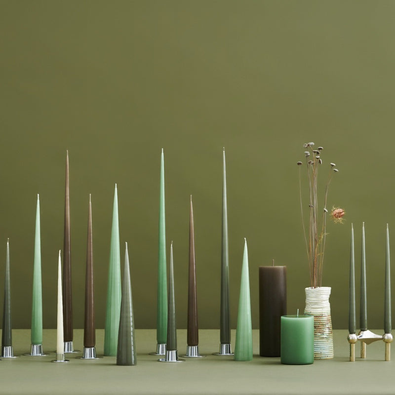 Set of tall, slender candles in various colors against a green background