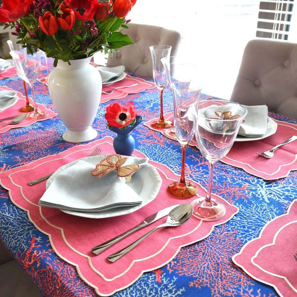 Decorative table setting with pink and blue tablecloth, floral centerpieces, and place settings.