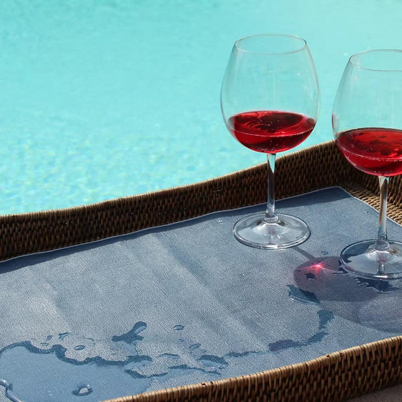 Two glasses of red wine on a tray by a pool
