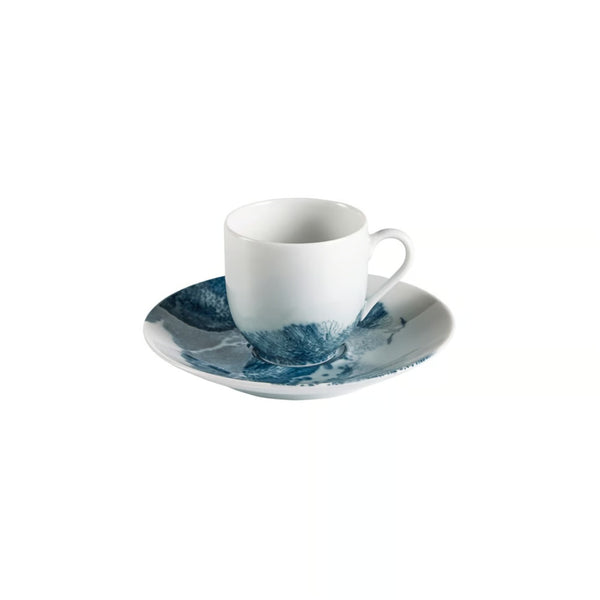 White porcelain cup and saucer with blue abstract design on a white background