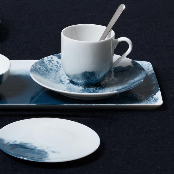 White porcelain cup and saucer with blue deep sea design on a dark background