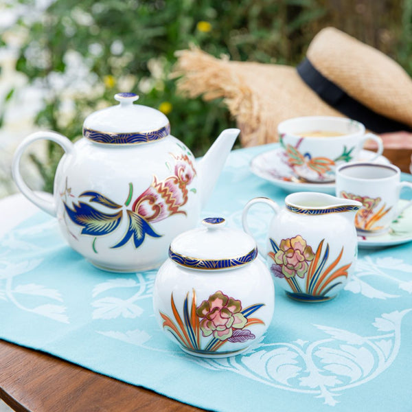 Decorative porcelain tea set Imari by Raynaud with floral patterns on a table outdoors.