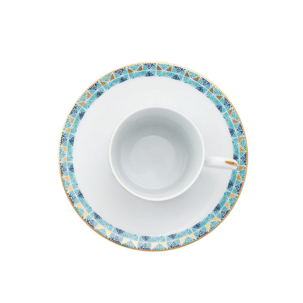 White teacup and saucer with decorative blue and gold rim on a white background