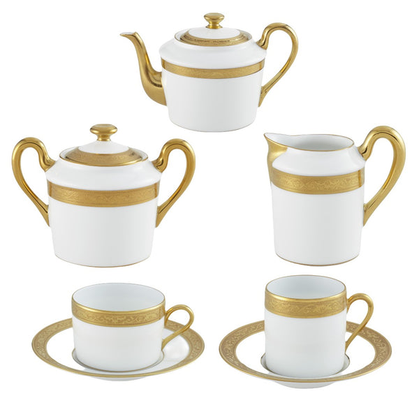 A set of white porcelain coffee/tea set with gold borders, including cups, saucers, a teapot, a sugar bowl, and a creamer, displayed against a neutral background.