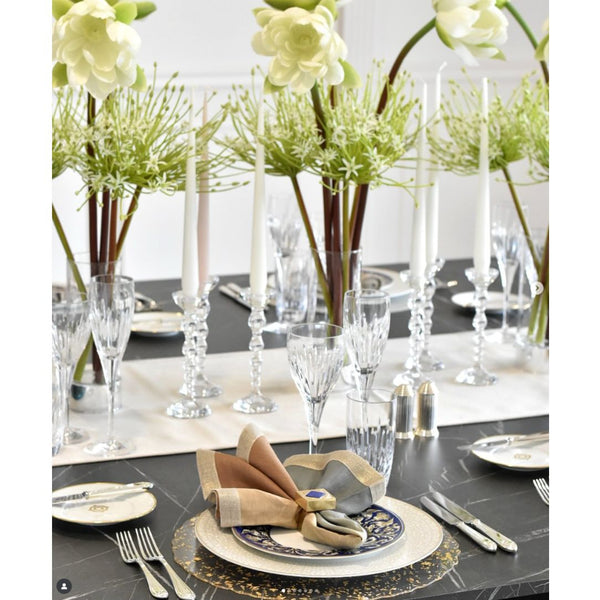 Elegant table setting with flowers, glasses, and cutlery on a black tablecloth.