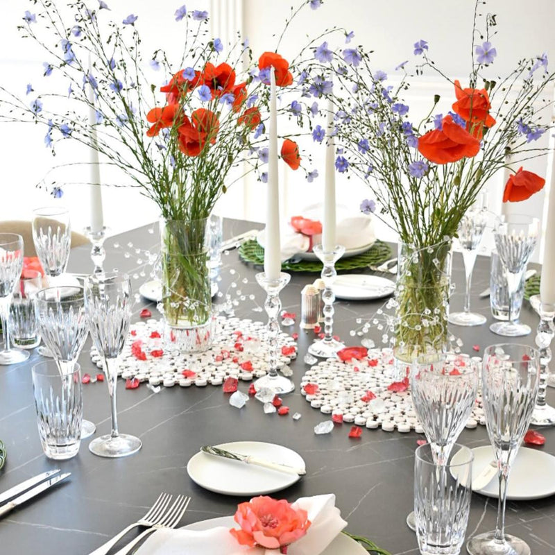 Decorative table setting with floral centerpieces, glasses, and cutlery on a dark surface.