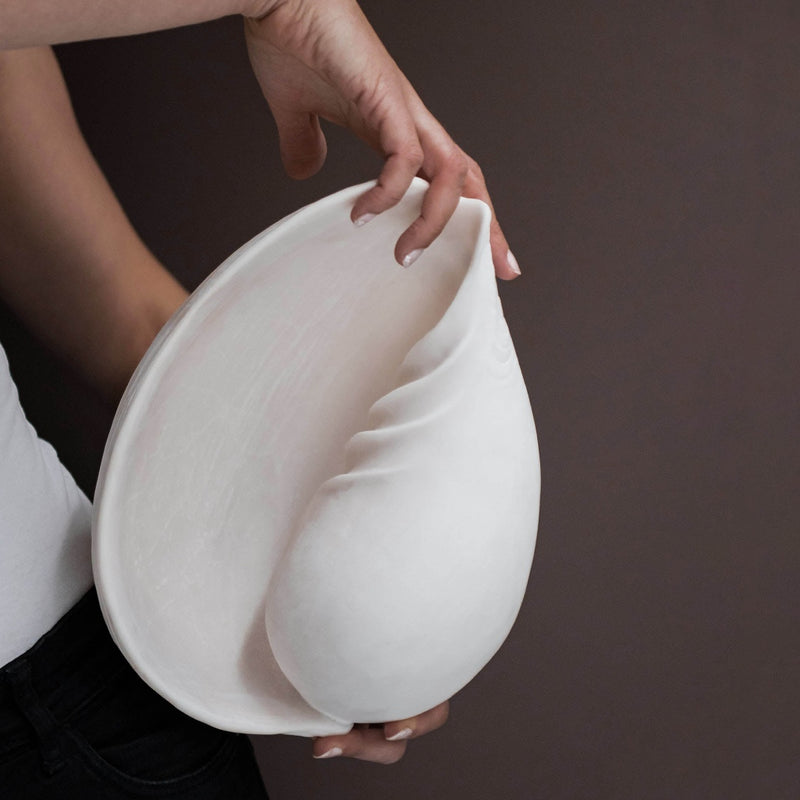 Large off-white faux conch shell decor held in hand