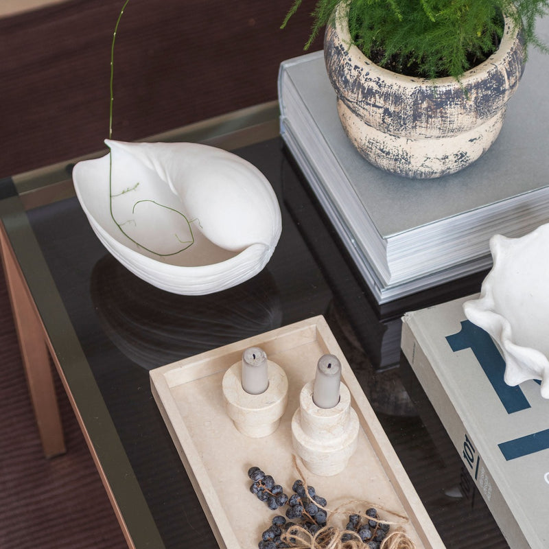 Small off-white faux conch shell styled on a coffee table