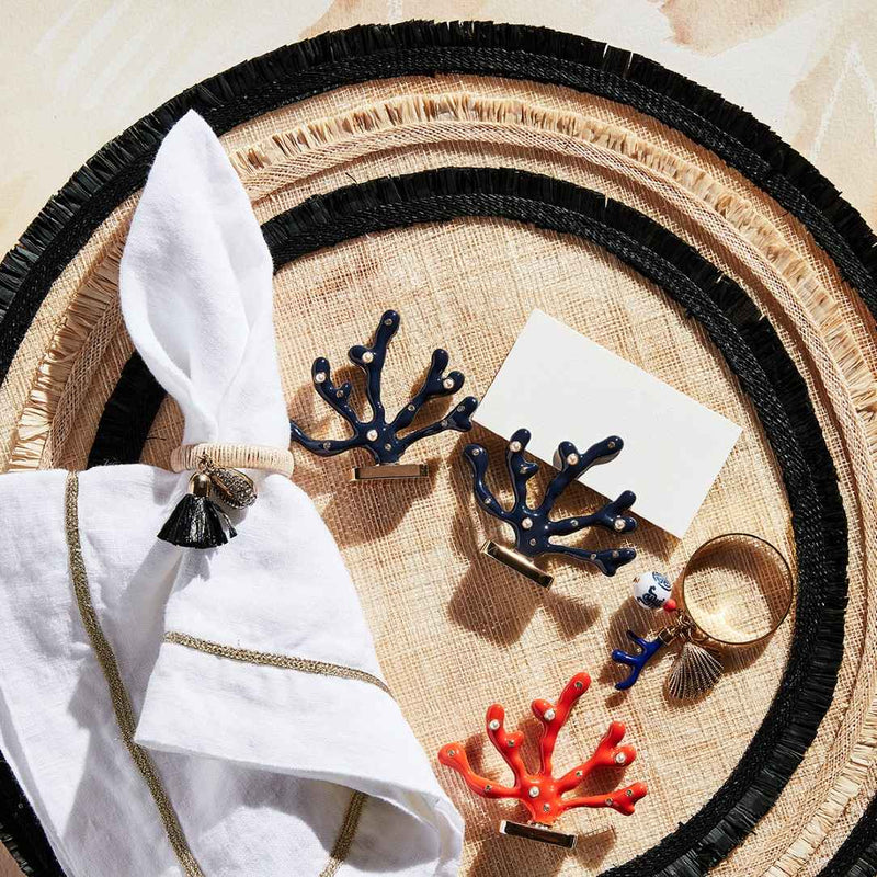 Decorative table setting with white napkins, black coral-shaped holders, and Coral-shaped place card holder in coral enamel with gold and crystal accents by Joanna Buchanan