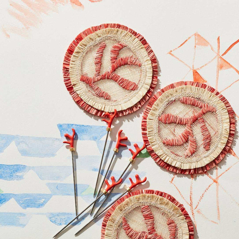 Decorative coasters with red and beige patterns on a colorful abstract background