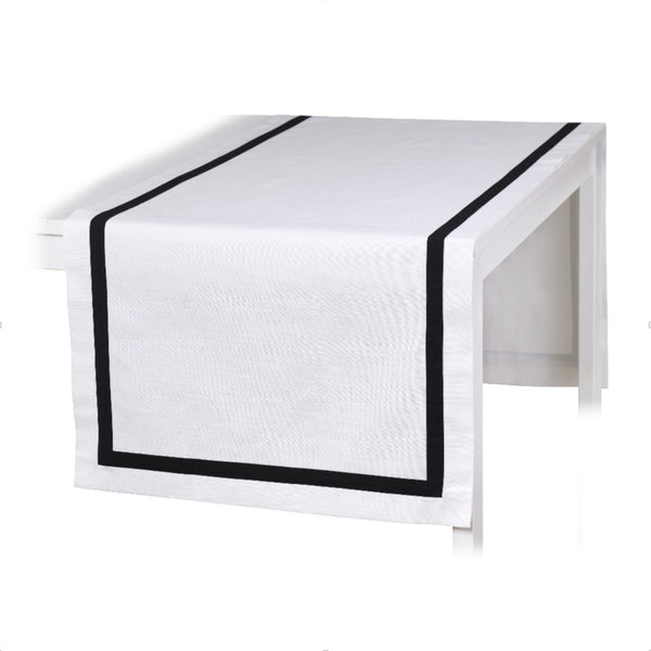 A white cotton table runner with black stripe border displayed on a table.