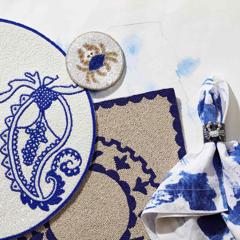 Decorative items including a round crab coaster, a small round woven item with a design, and a folded fabric with blue patterns on a white background.