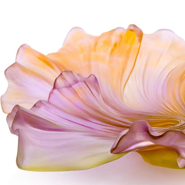 Close-up of a glass sculpture resembling a flower with pink, yellow, and orange colors on a white background.