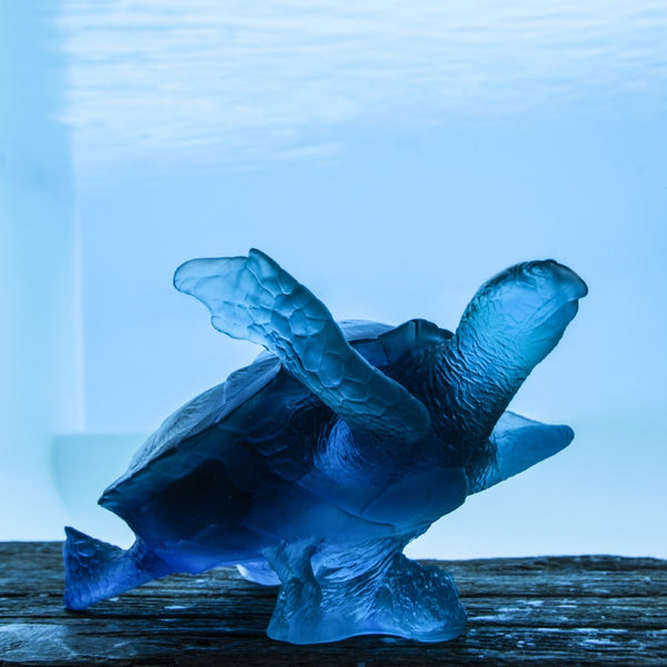 Blue turtle sculpture on a wooden surface with a blue gradient background