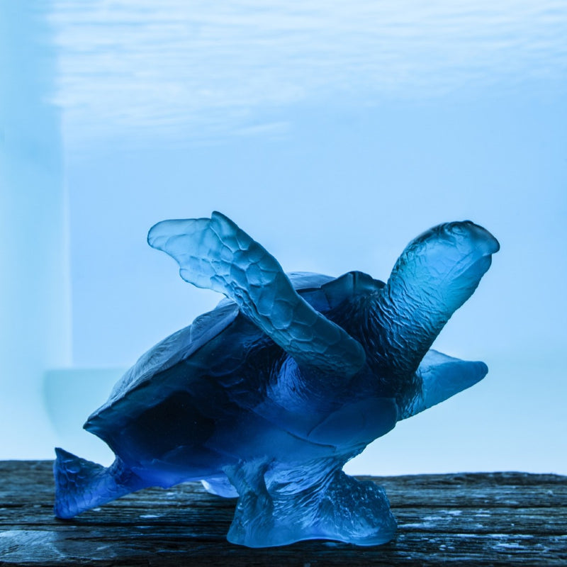 Blue turtle sculpture on a wooden surface with a blue gradient background