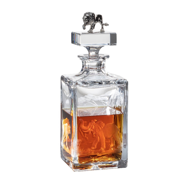 Clear glass decanter with engraved elephant design and lion emblem on a white background