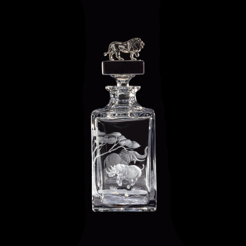 Clear glass decanter with engraved designs of a lion and rhinoceros on a black background