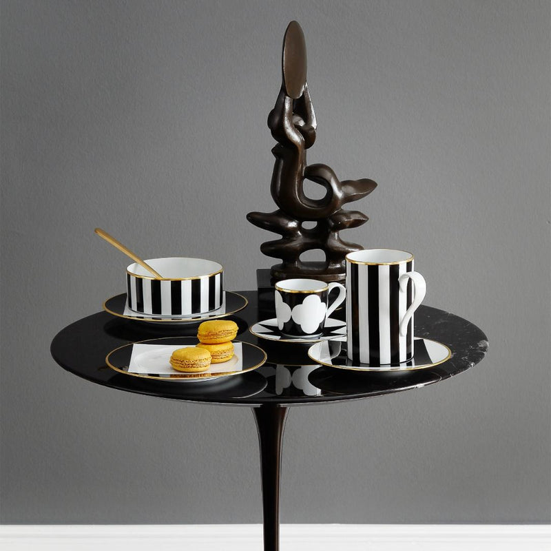 small porcelain bowl in cylindrical shape decorated with black and white stripes from the ca d oro collection by sieger furstenberg on a small round table against a gray background