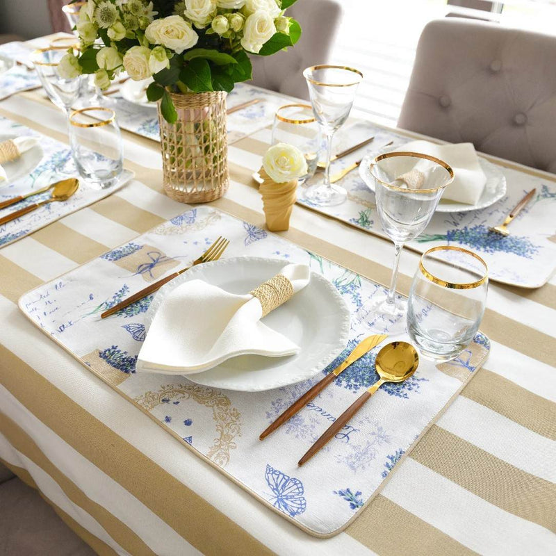 Elegant table setting with striped tablecloth, floral centerpiece, and decorative placemats.