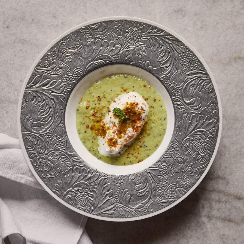 Green soup with a dollop of cream and a sprinkle of spices in a Porcelain deep plate with rim and platinum detailing from the Italian Renaissance Platinum collection by Raynaud.