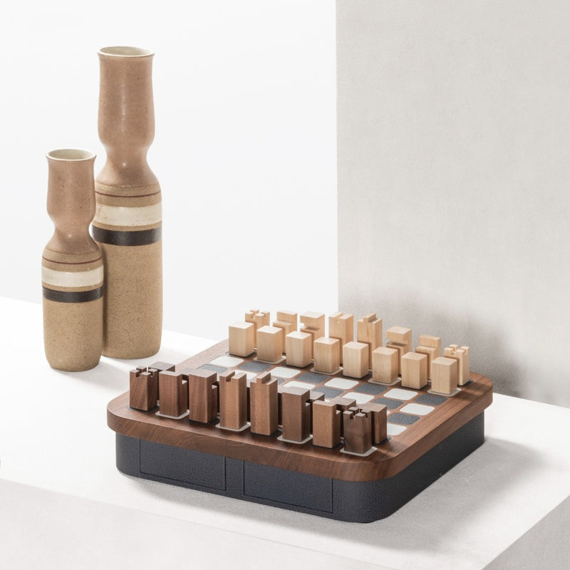 Wooden chess set with two vases on a white surface