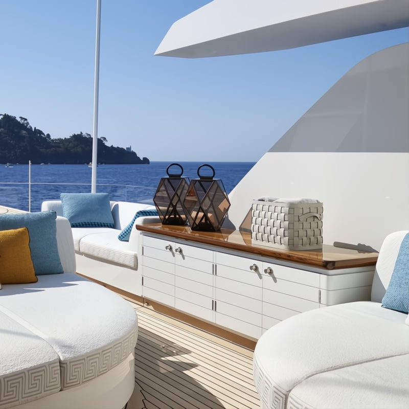 Yacht deck with white furniture, blue cushions, and a Demetra large rectangular storage basket in brown regenerated leather by Pinetti with smooth leather lid and handwoven detailing