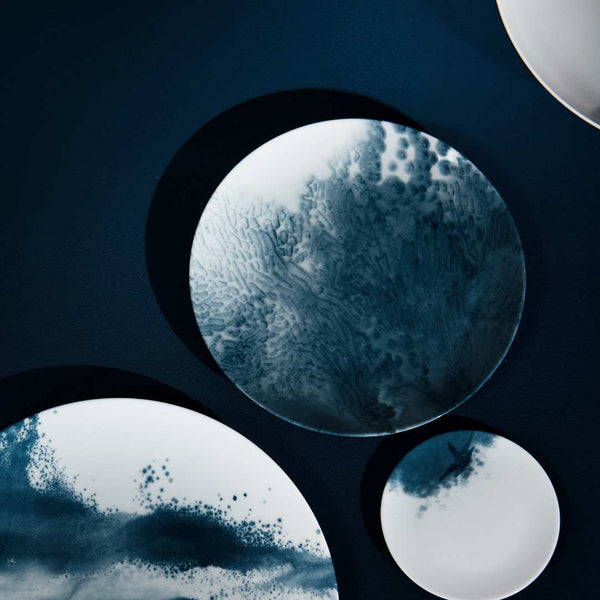 Indigo Abysses porcelain dessert plate by Raynaud on a dark background