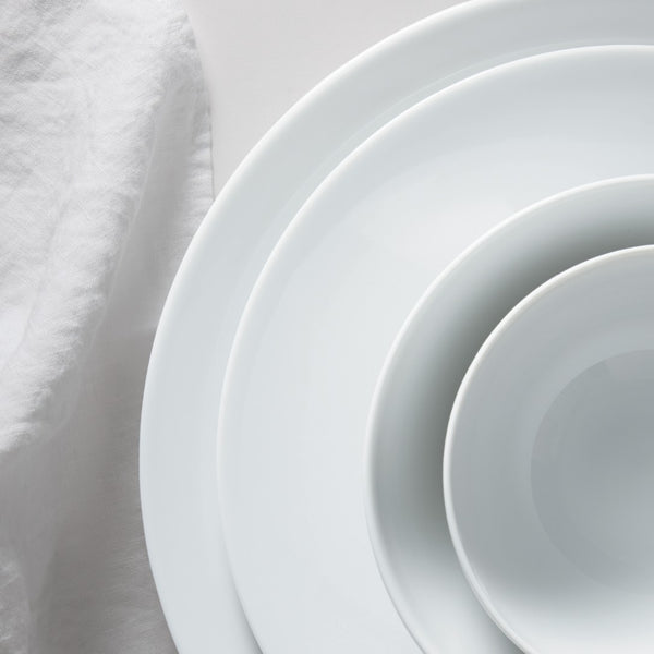 Stack of white ceramic plates on a light fabric background