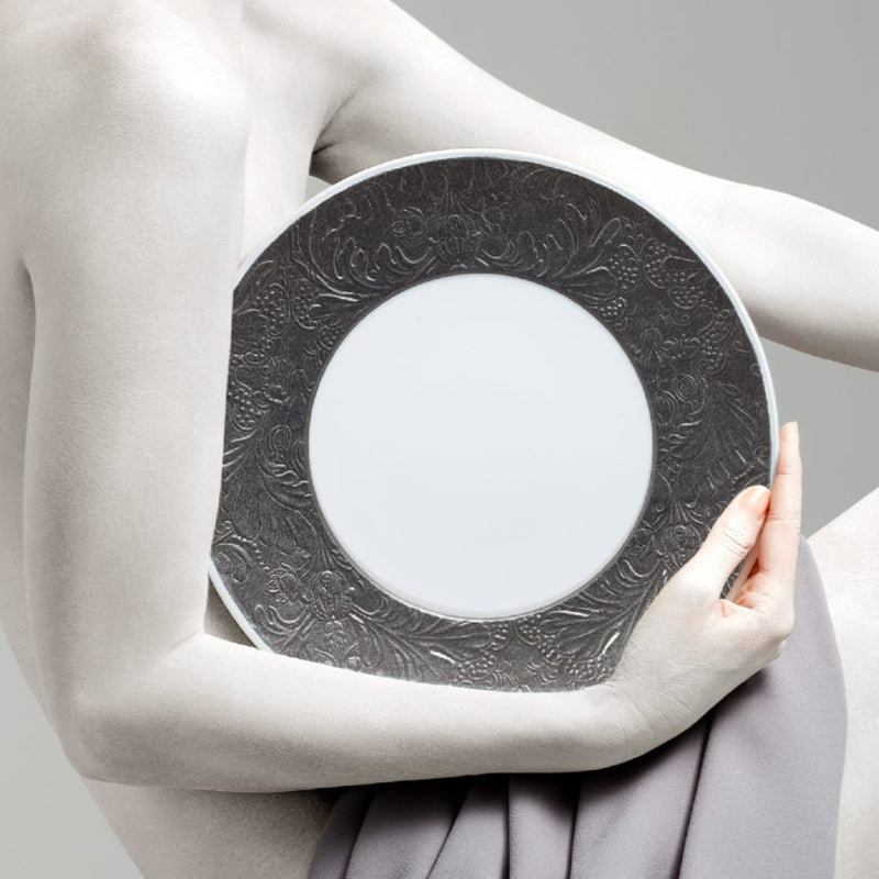 Person holding a dinner plate italian renaissance platinum by Raynaud against a neutral background