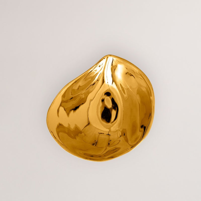 Gold teardrop-shaped plate on a light gray background