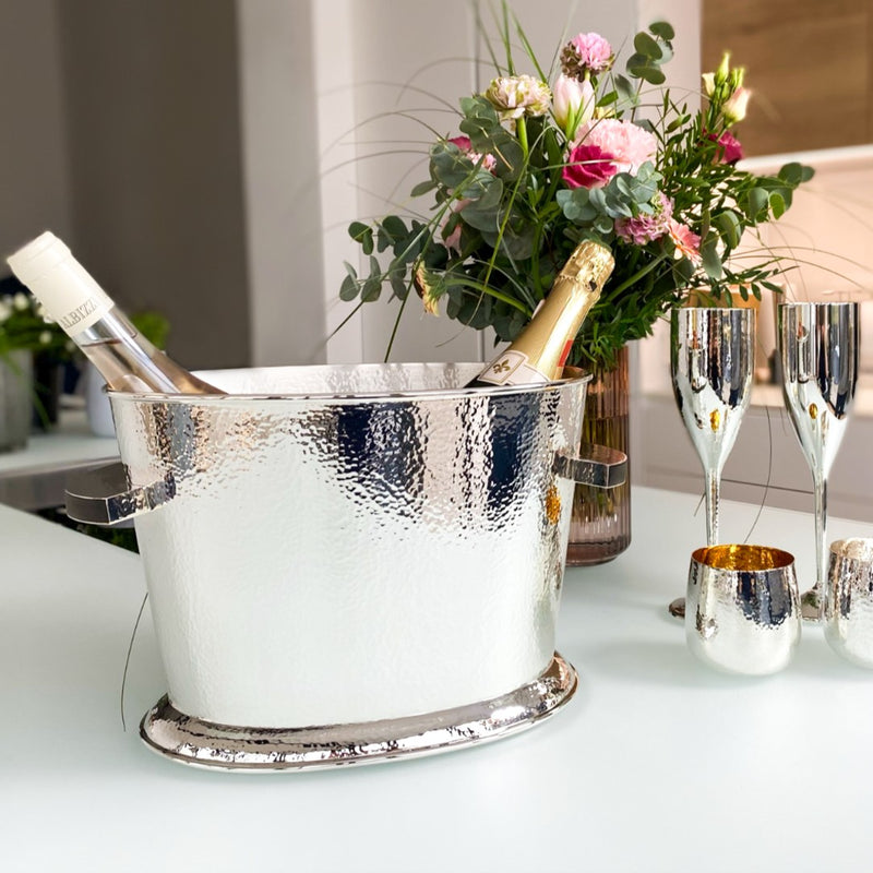 Styled table with flowers and Double champagne cooler in hammered silver-plated finish by Sonja Quandt, holding two bottles