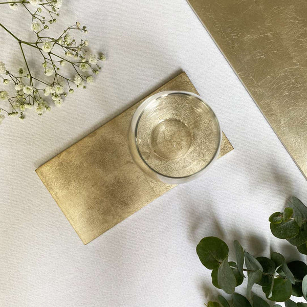 Gold coaster with a textured surface on a white background with gold accents