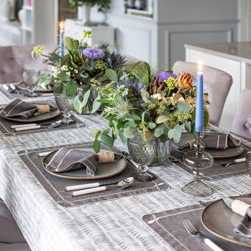 Elegant dining table setting with floral centerpieces, candles, and patterned tablecloth.