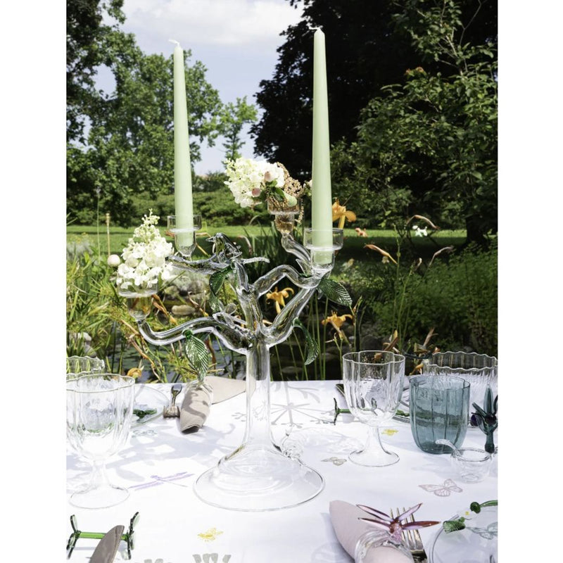 Decorative glass candelabra with candles on a table outdoors.