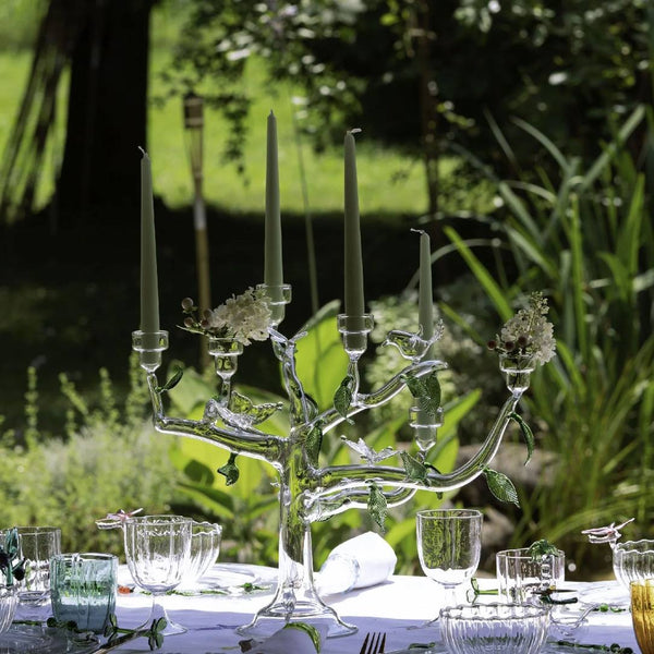 Decorative glass candelabra with candles on a table outdoors.