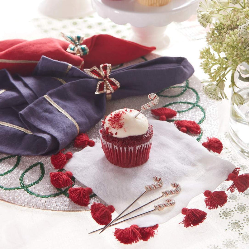 Red velvet cupcake with white frosting on a decorative napkin with red tassels and gold accents.