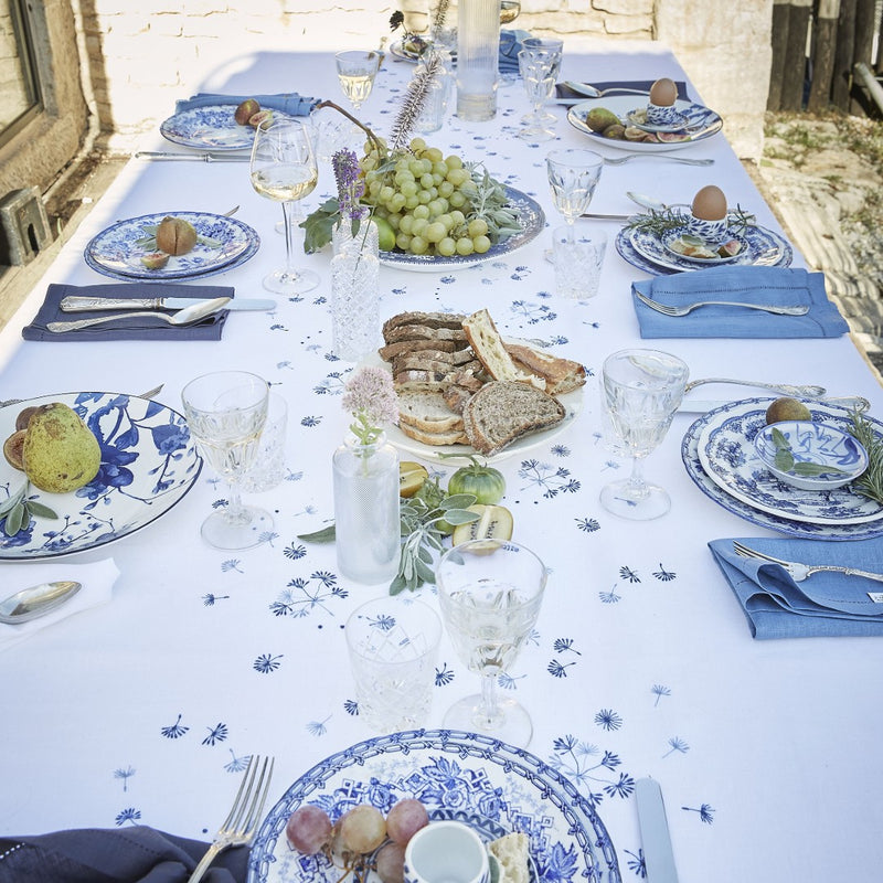 white tablecloth with blue flowers featuring tableware and bread basket
