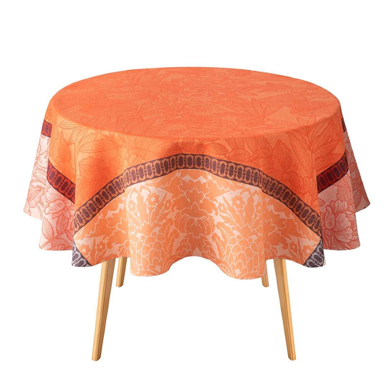 Round table with an orange floral-patterned tablecloth on a white background