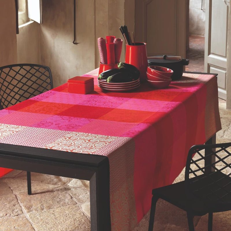 Dining table with a red and pink checkered tablecloth, surrounded by chairs.