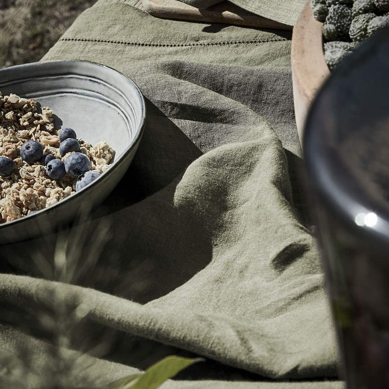 Bowl of granola with blueberries on a textured fabric surface