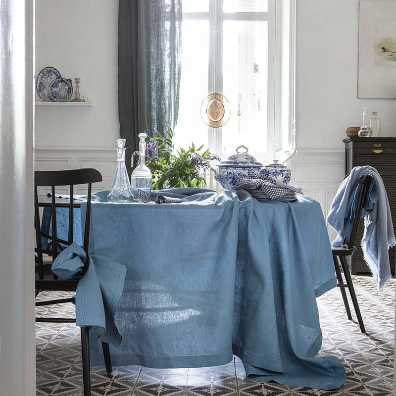 Dining room with a table covered in a blue tablecloth, chairs, and decorative items.