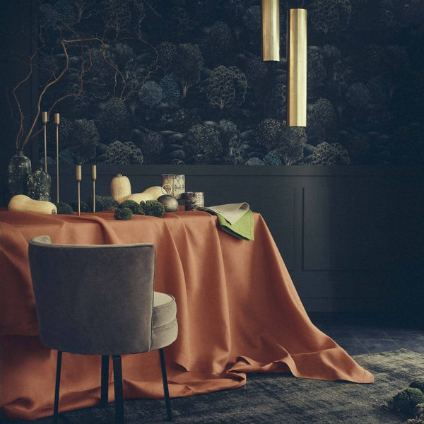 Dining room with a table draped in an orange tablecloth, gray chair, and dark floral wallpaper.